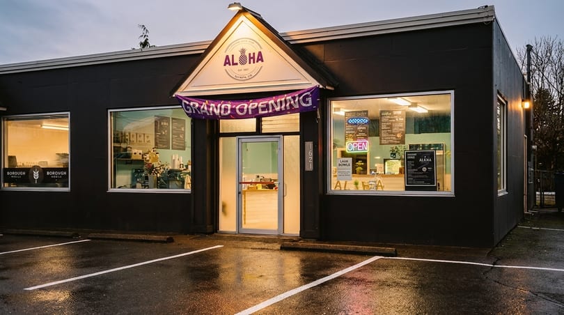 The Aloha restaurant exterior at dusk, with a "Grand Opening" banner and illuminated windows.